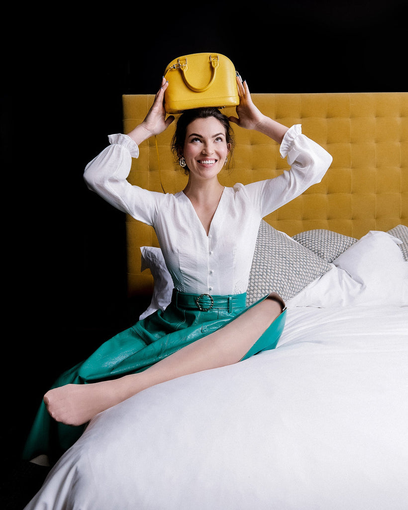 a woman wearing a yellow hat sitting on a bed 